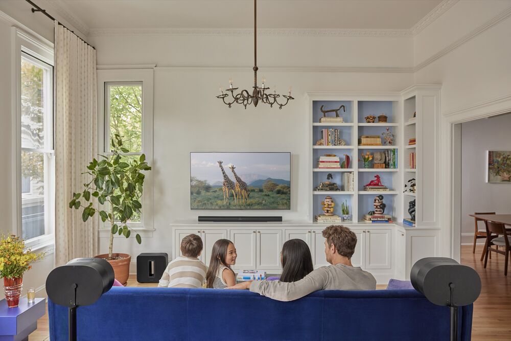 Family watching TV in a bright living room with Sonos sound